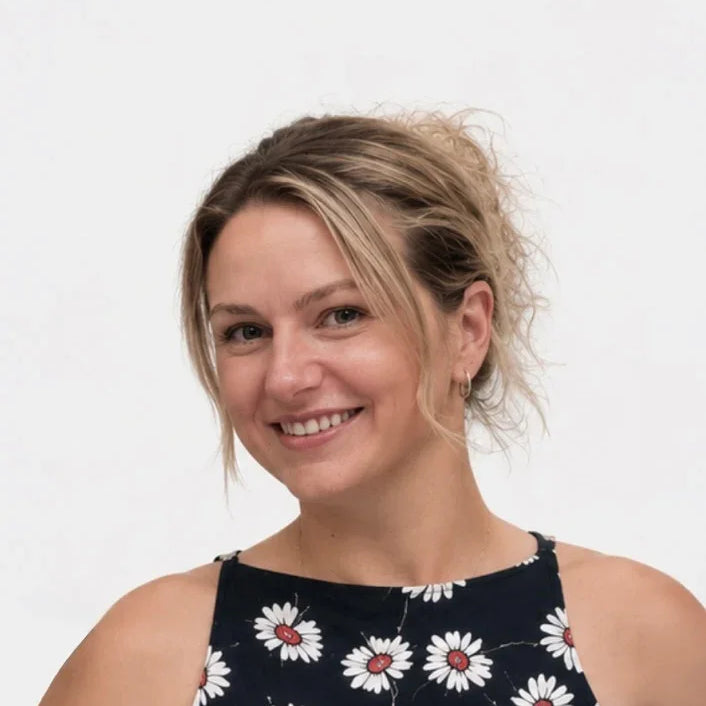 Woman wearing a black sleeveless top with white floral patterns on a plain background
