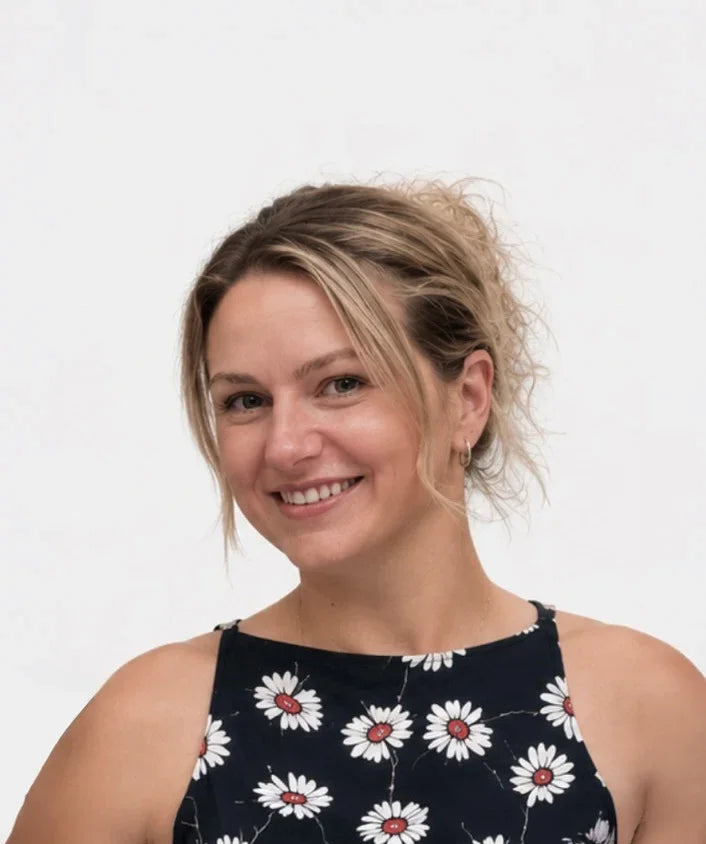 Woman wearing a black sleeveless top with white floral patterns on a plain background
