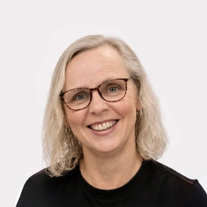 Person with gray hair and glasses wearing a black shirt on a white background