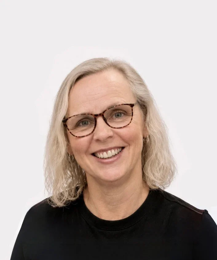 Person with gray hair and glasses wearing a black shirt on a white background