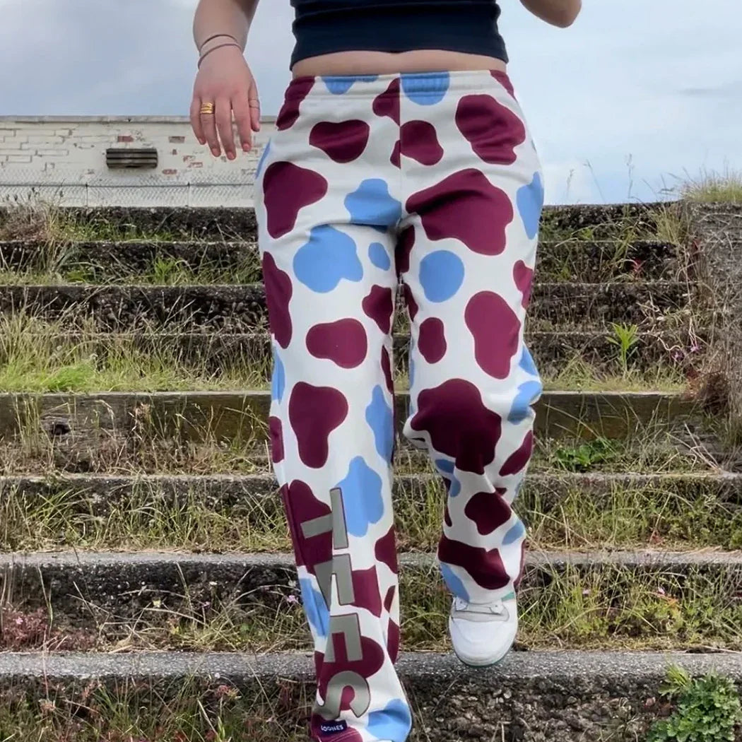 Person wearing colorful polka dot pants with a brand logo on outdoor steps.