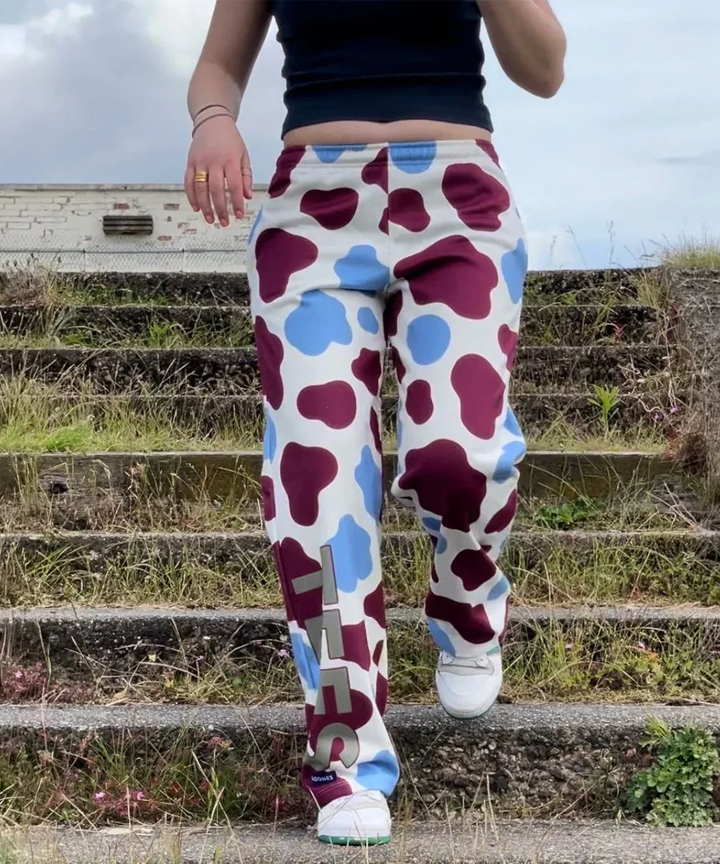 Person wearing colorful polka dot pants with a brand logo on outdoor steps.